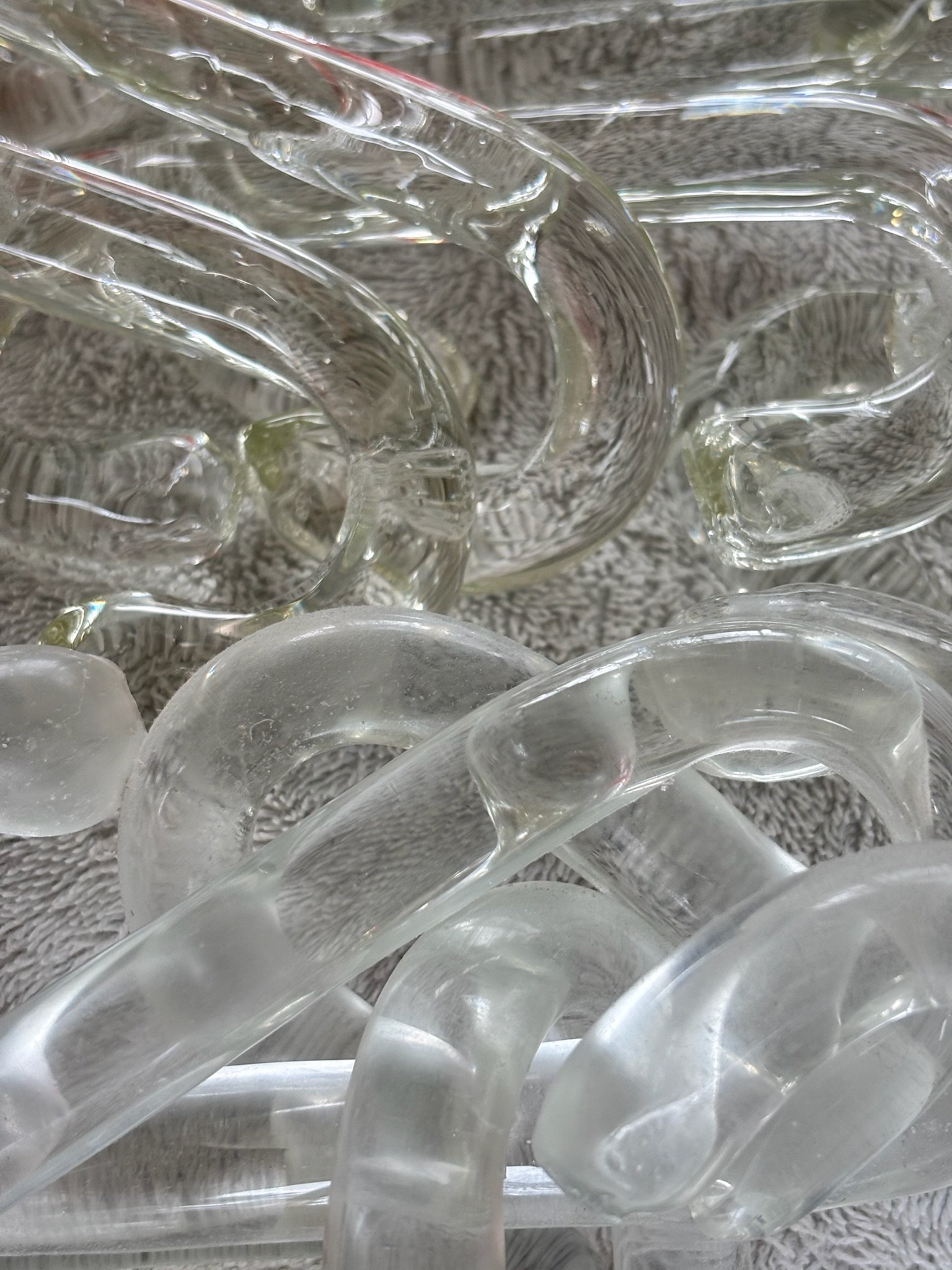 Close-up of handblown glass chain links being cleaned on microfiber towel