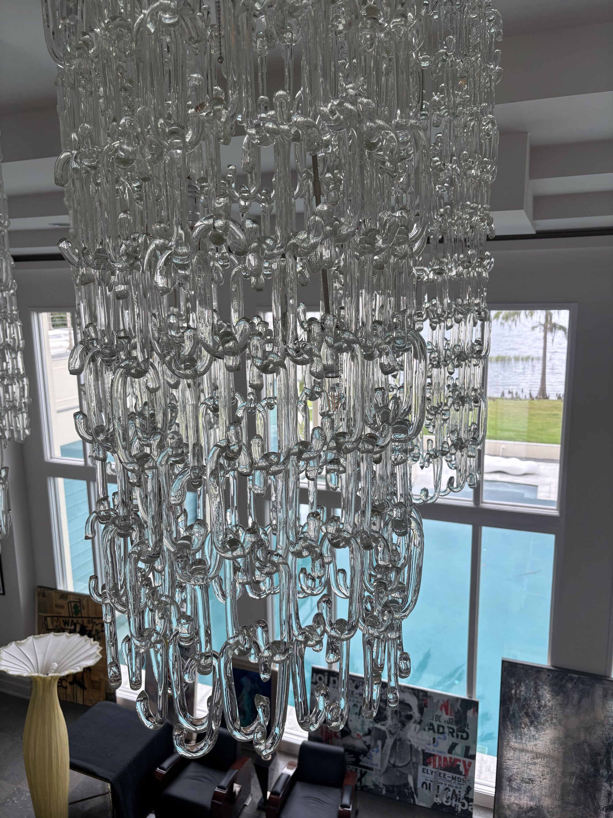 Handblown glass chain-link chandelier close-up with pool visible through windows