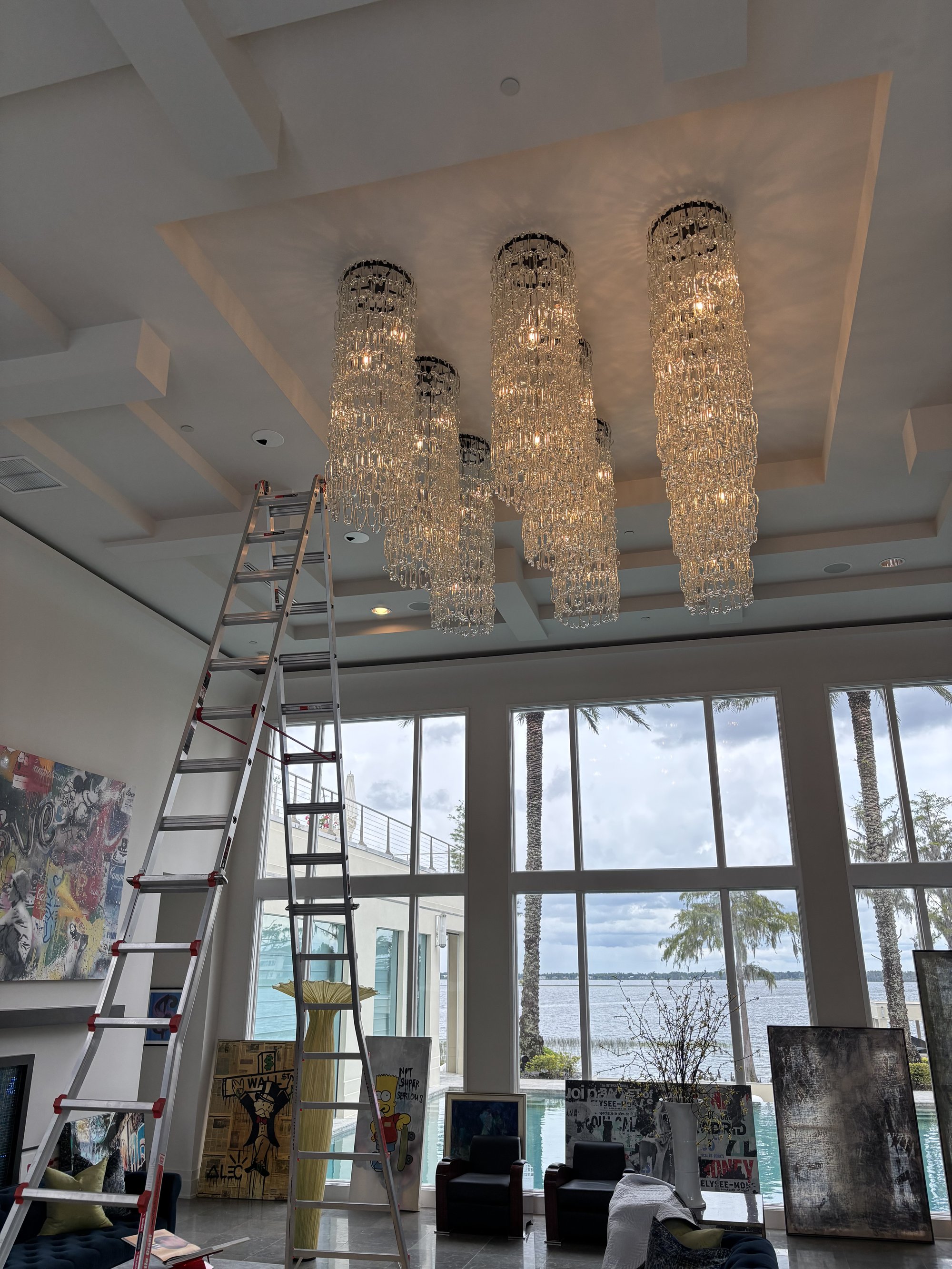 Four of the nine handblown glass chandeliers with ladder setup in Orlando luxury home