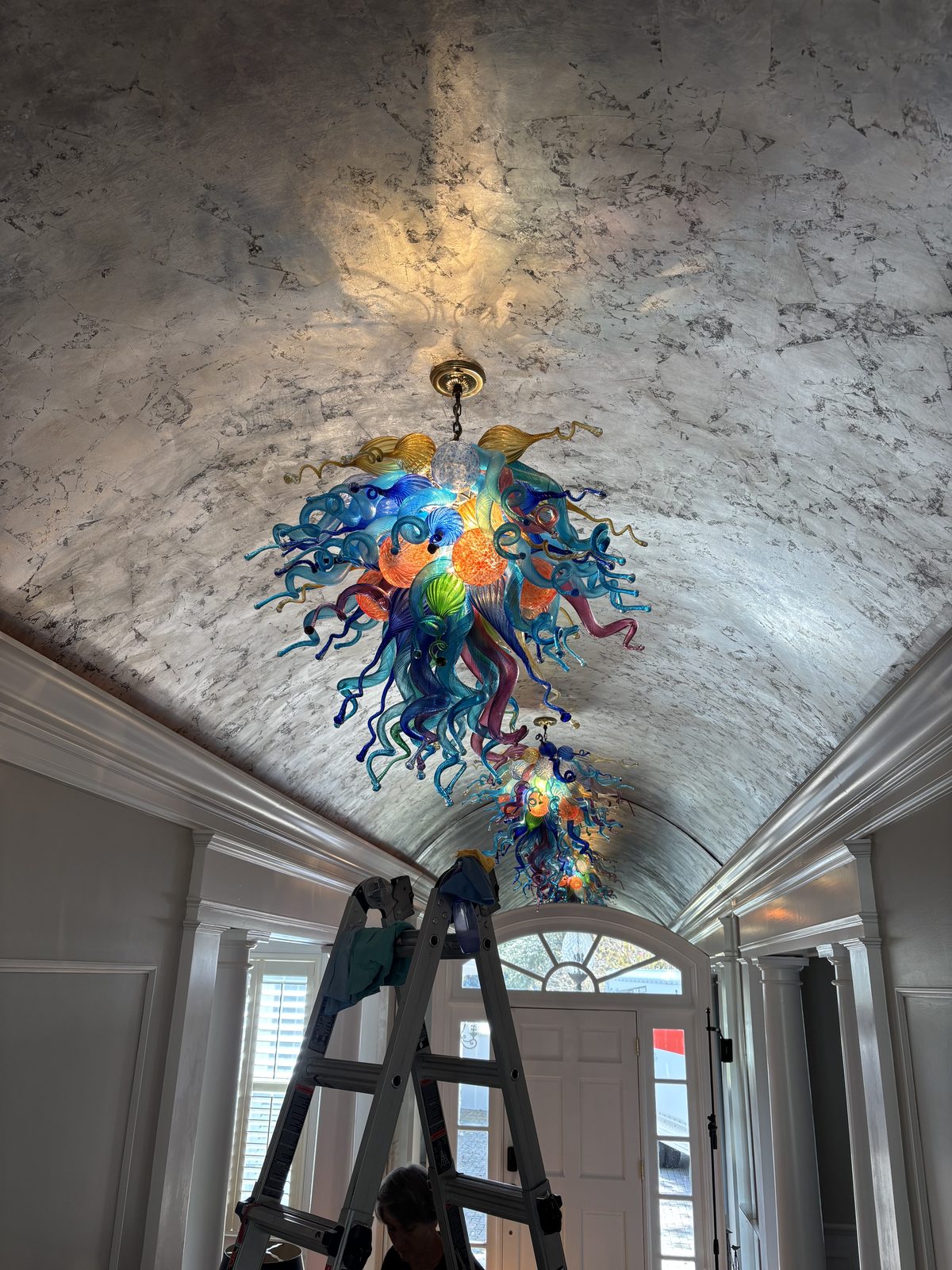 Professional chandelier cleaner working on Chihuly handblown glass art installation