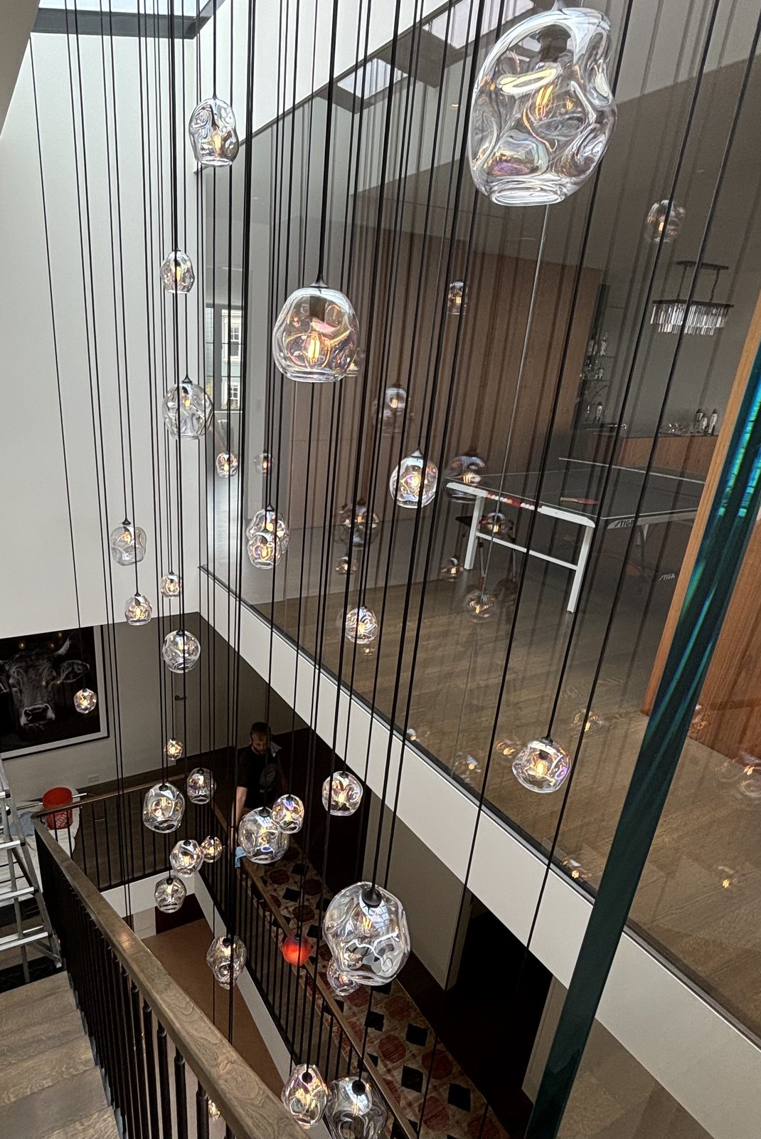 Close-up of handblown iridescent glass pendants with glass office wall behind