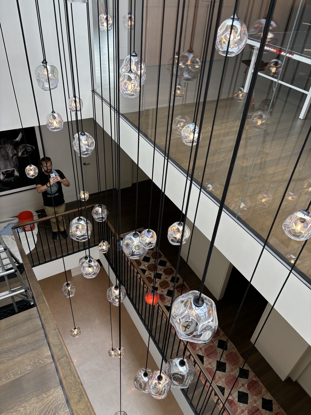 View looking down 4-story stairwell showing all 40 glass pendants, glass wall, and cleaning setup