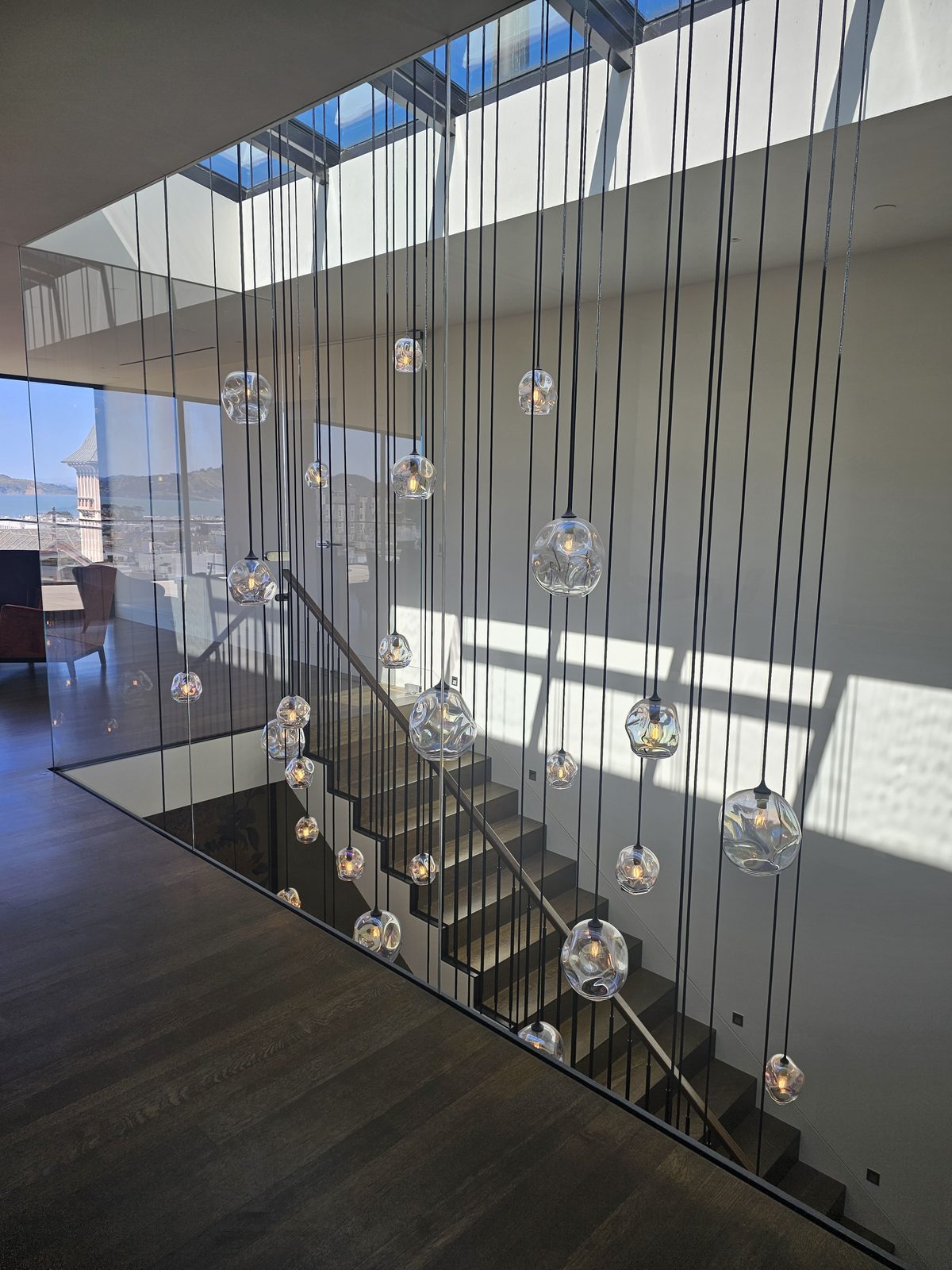 Looking up through 4-story stairwell at 40 handblown glass pendants suspended on black cables