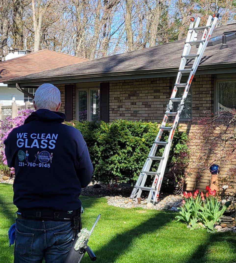 Window cleaner with ladder at brick home