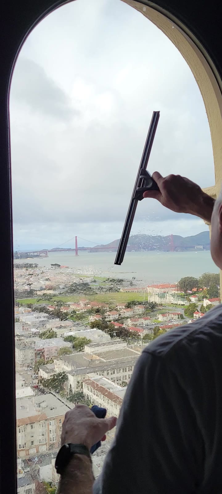 Squeegee cleaning window with Golden Gate Bridge view