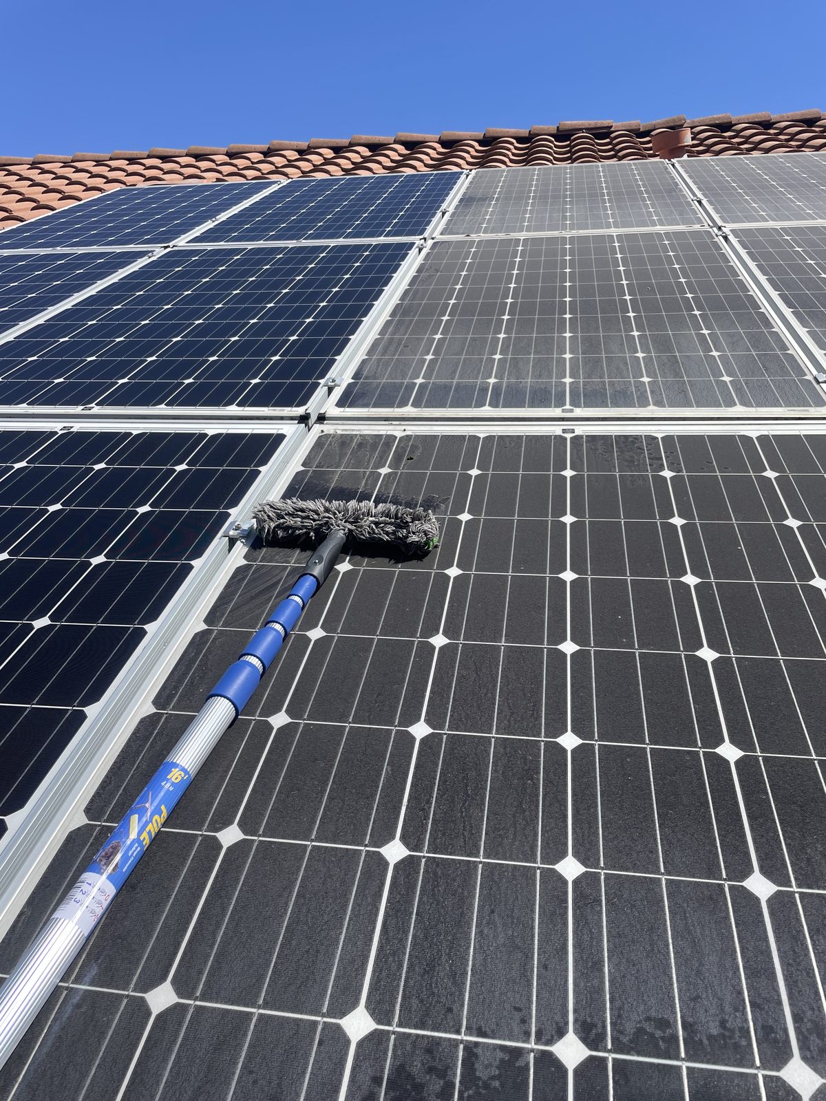 Close-up of solar panel being scrubbed with professional brush showing dirty vs clean contrast